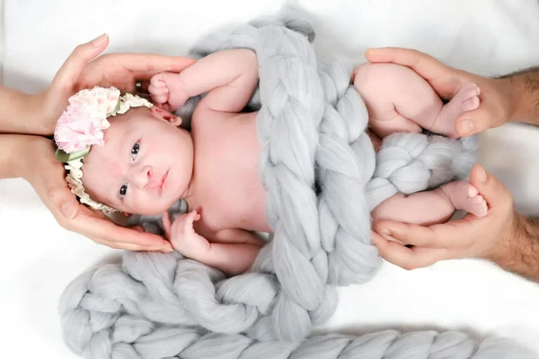 un bébé entre les mains de ses parents.
